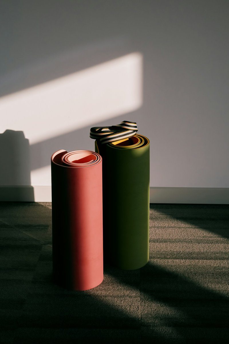 Deux tapis roulés posés au sol dans un rai de lumière
